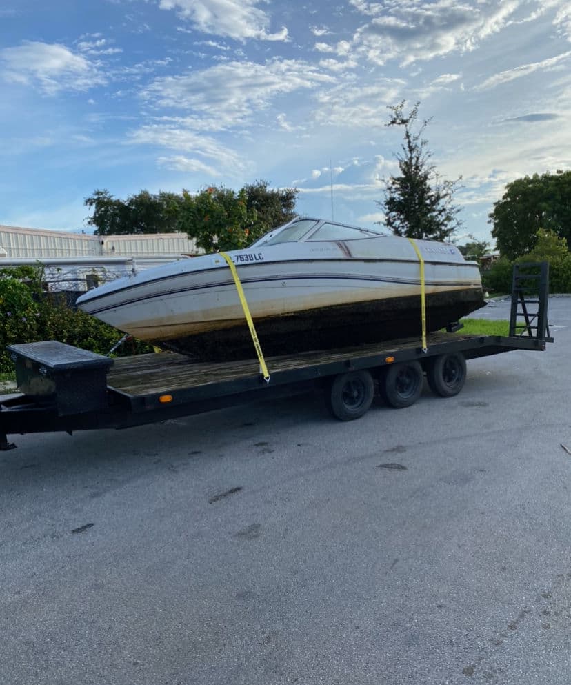 Boat on trailer ready for transportation, parked in a driveway under a clear sky.
