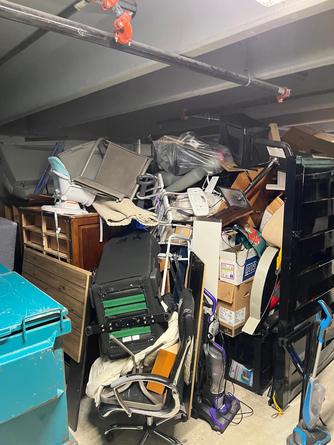 Cluttered storage area filled with various furniture and boxes, showcasing disorganization.