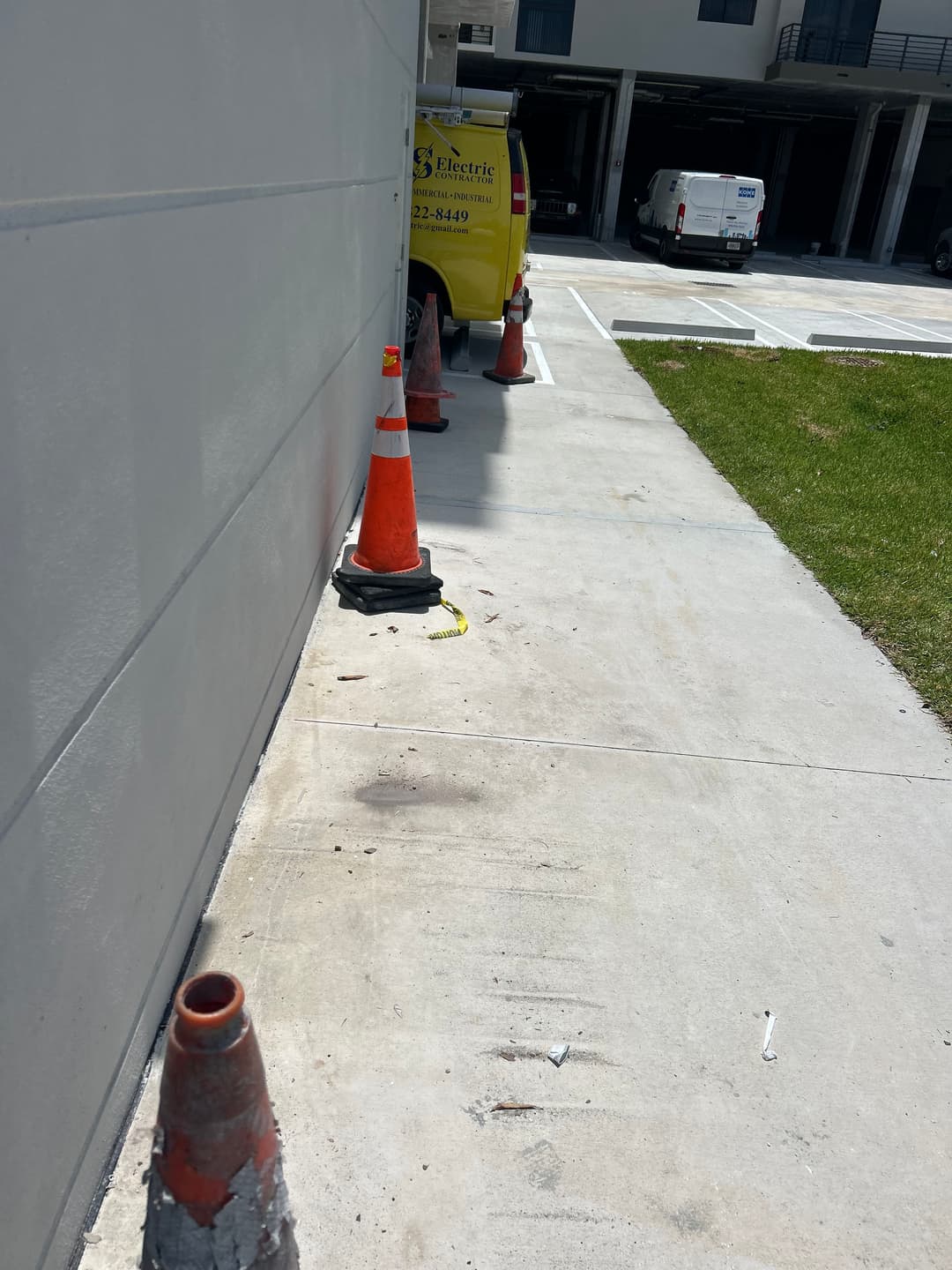Construction area with traffic cones, a utility van, and a clean concrete sidewalk.