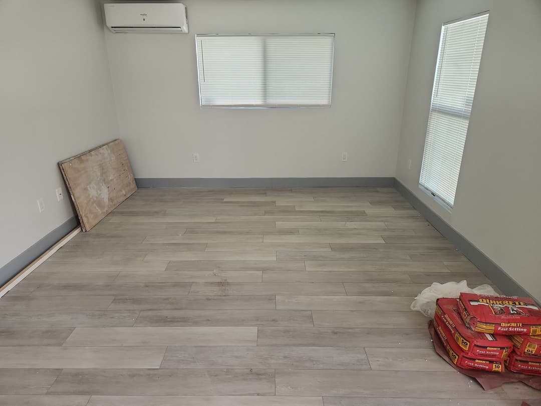 Empty room with gray walls, new flooring, and construction materials in the corner.