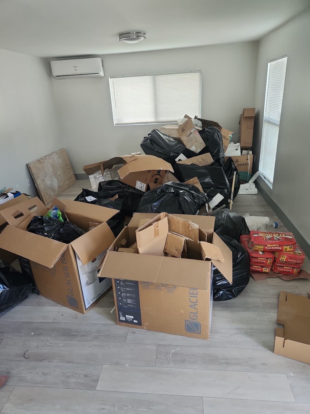 Messy room filled with cardboard boxes and trash bags scattered on the floor.